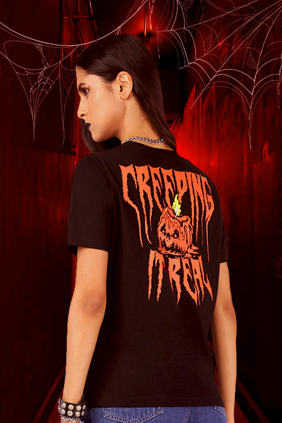 A women wearing black tshirt with a graphic print on the back which have a pumkin and a text saying " Creeping it Real ".